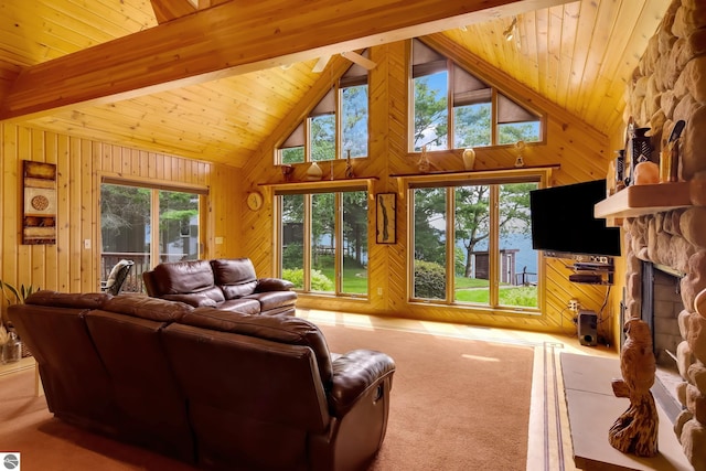 carpeted living room with a fireplace, wooden walls, plenty of natural light, and high vaulted ceiling