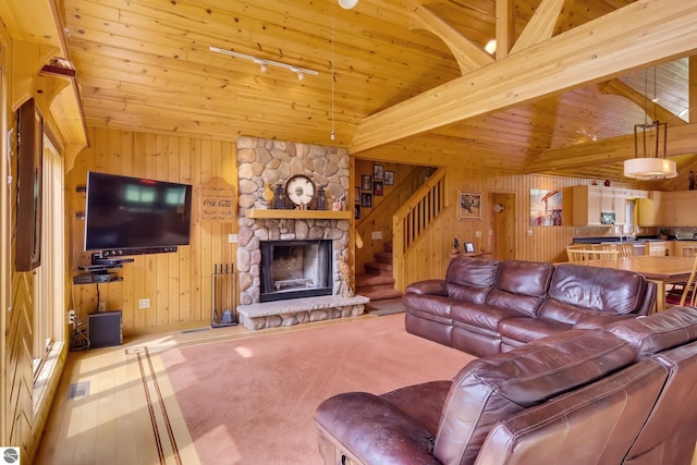 living room featuring vaulted ceiling with beams, a stone fireplace, wooden ceiling, and wooden walls