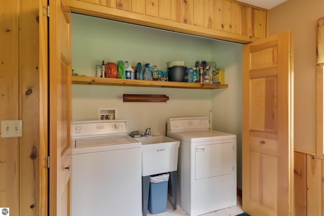 clothes washing area featuring independent washer and dryer and wood walls