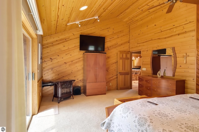 carpeted bedroom with wooden walls, a wood stove, wood ceiling, and vaulted ceiling