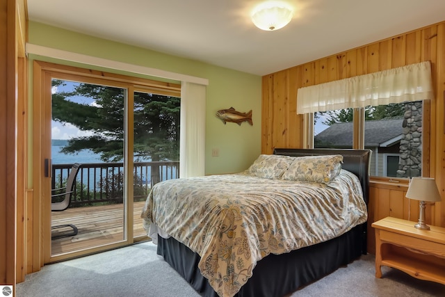 carpeted bedroom with access to outside and wooden walls