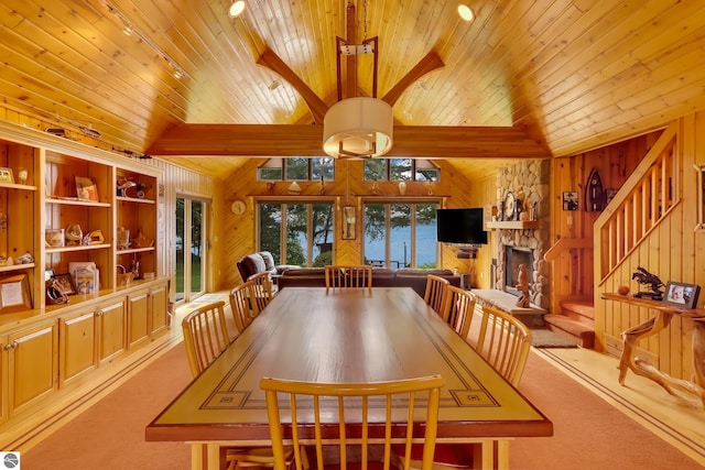 dining room featuring carpet, wood ceiling, wooden walls, high vaulted ceiling, and a fireplace