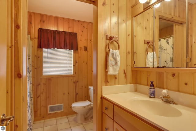 bathroom featuring tile patterned flooring, vanity, toilet, and wooden walls