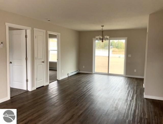 empty room featuring a chandelier, a baseboard heating unit, and dark hardwood / wood-style floors