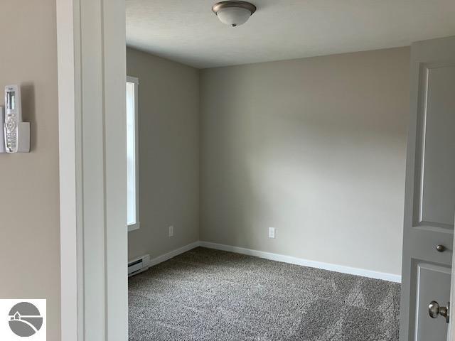 unfurnished room featuring baseboard heating and carpet floors