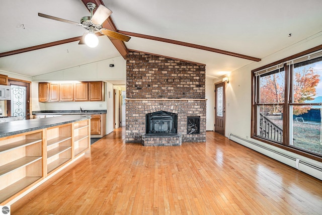 unfurnished living room featuring sink, lofted ceiling with beams, a baseboard heating unit, light hardwood / wood-style floors, and a fireplace