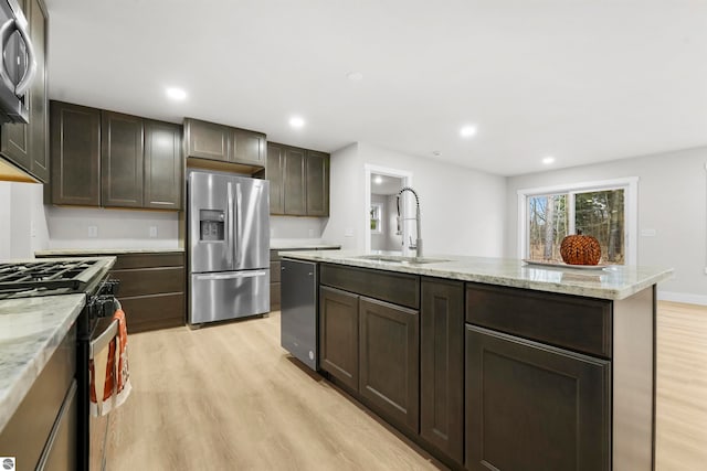 kitchen with appliances with stainless steel finishes, light hardwood / wood-style flooring, a kitchen island with sink, and sink