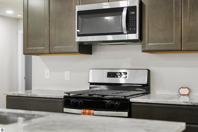 kitchen with light stone countertops, dark brown cabinetry, and stainless steel appliances