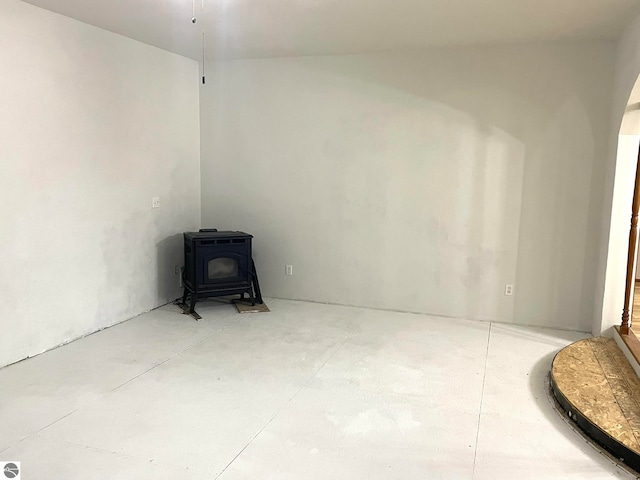 unfurnished room with concrete flooring and a wood stove