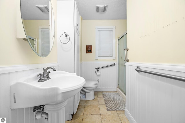 bathroom with tile patterned flooring, an enclosed shower, a textured ceiling, and toilet