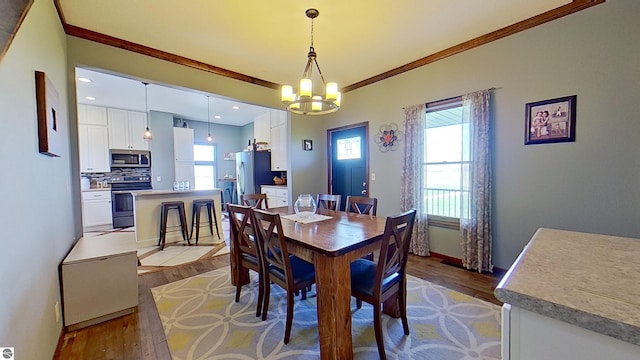 dining space featuring hardwood / wood-style floors, ornamental molding, and a notable chandelier