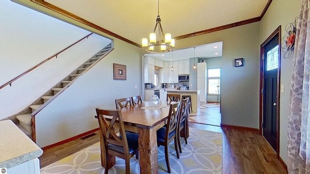 dining space with a chandelier, ornamental molding, and light hardwood / wood-style flooring