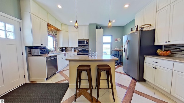 kitchen with decorative backsplash, stainless steel appliances, a kitchen island, and white cabinetry