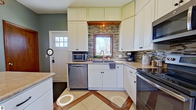 kitchen with decorative backsplash, appliances with stainless steel finishes, and white cabinetry