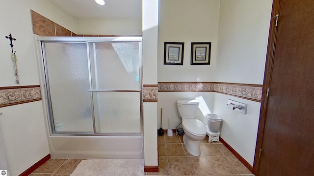 bathroom featuring tile patterned floors, toilet, and bath / shower combo with glass door