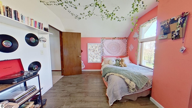 bedroom featuring multiple windows, lofted ceiling, and hardwood / wood-style flooring