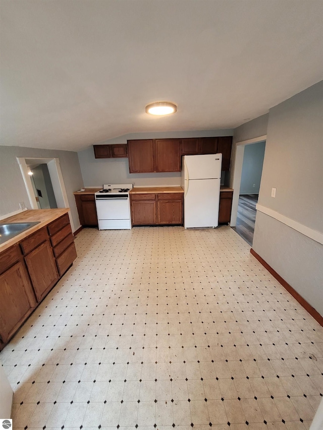 kitchen featuring vaulted ceiling, sink, and white appliances