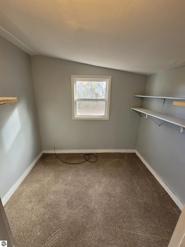 spare room featuring carpet flooring and vaulted ceiling