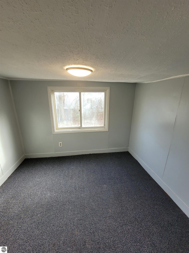 unfurnished room featuring dark carpet and a textured ceiling