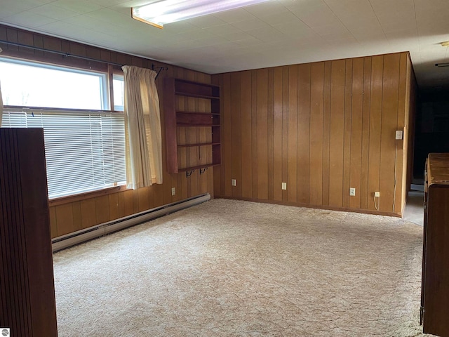 empty room featuring wooden walls, light colored carpet, and a baseboard heating unit