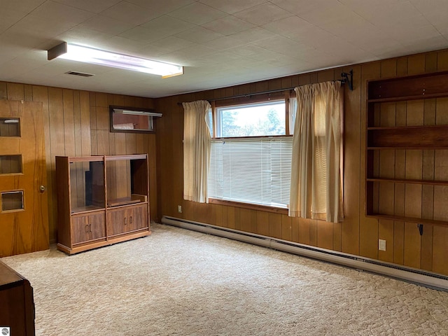 unfurnished living room featuring light colored carpet, wooden walls, and a baseboard radiator