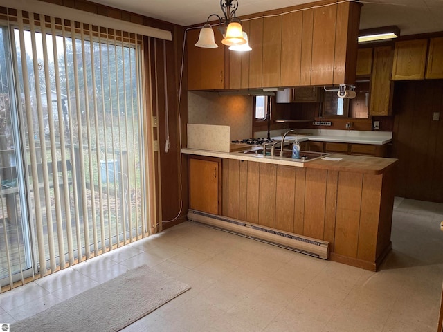 kitchen with a baseboard heating unit, sink, a wealth of natural light, decorative light fixtures, and kitchen peninsula