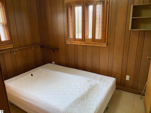 bedroom featuring light tile patterned floors and wood walls