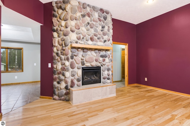 unfurnished living room featuring hardwood / wood-style floors and a stone fireplace