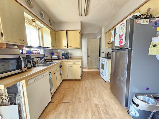 kitchen with tasteful backsplash, a sink, stainless steel appliances, light countertops, and light wood-type flooring