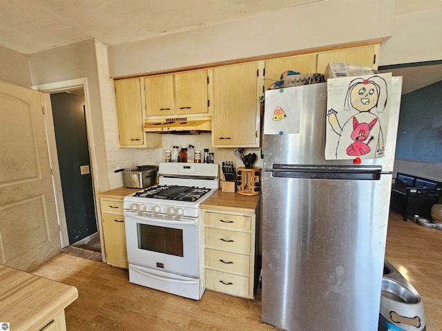 kitchen with gas range gas stove, tasteful backsplash, light wood-style flooring, freestanding refrigerator, and under cabinet range hood