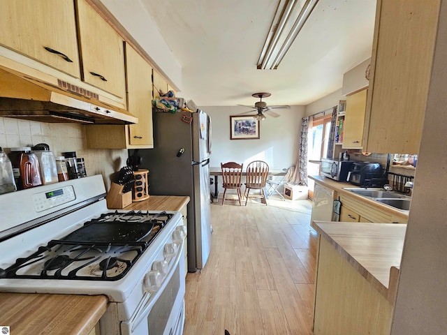 kitchen featuring under cabinet range hood, light wood-style floors, light brown cabinets, backsplash, and white appliances