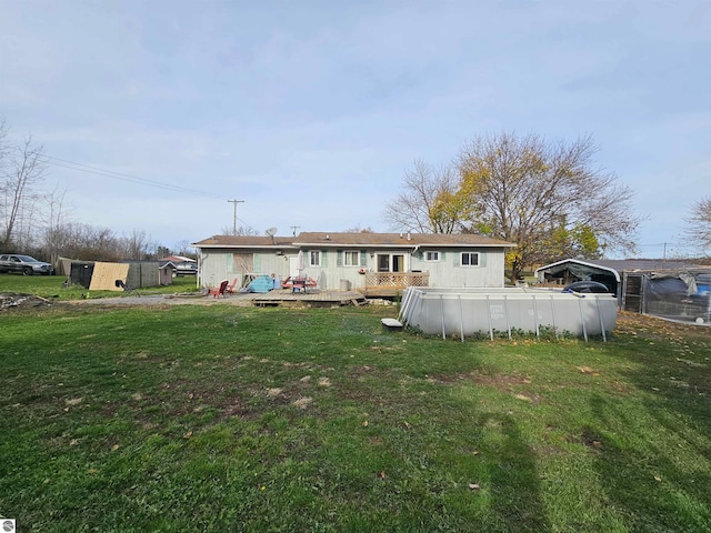 back of property featuring a swimming pool, a yard, and a wooden deck