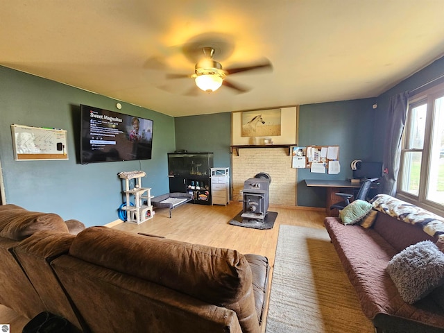 living room featuring hardwood / wood-style floors, ceiling fan, and a wood stove