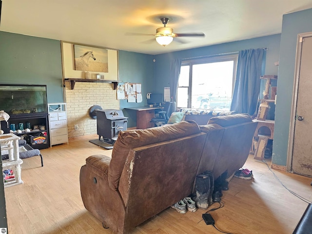 living room with a wood stove, wood finished floors, and a ceiling fan