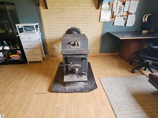office area featuring baseboards, a wood stove, and wood finished floors
