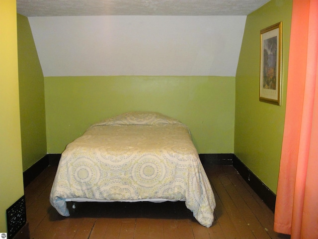 bedroom featuring a textured ceiling, dark hardwood / wood-style floors, and vaulted ceiling