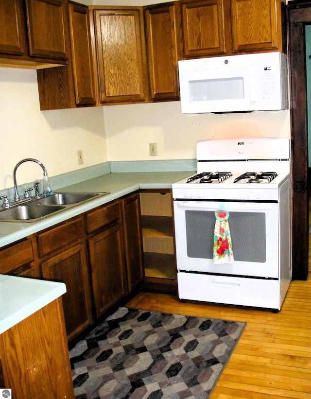 kitchen featuring white appliances, light hardwood / wood-style floors, and sink