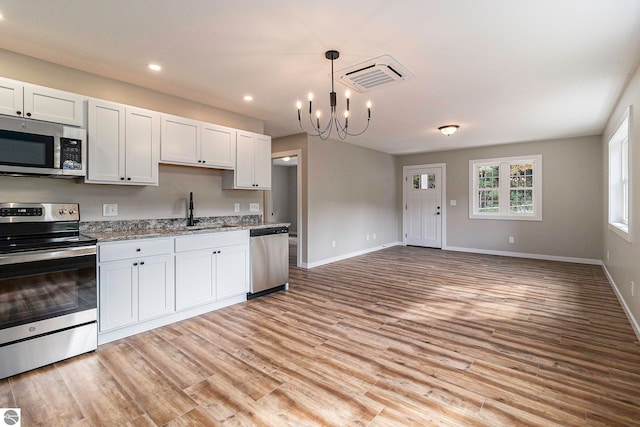 kitchen featuring hanging light fixtures, stainless steel appliances, light hardwood / wood-style flooring, a notable chandelier, and white cabinets