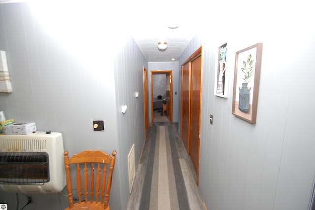 corridor featuring heating unit, wooden walls, and hardwood / wood-style flooring