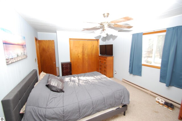 bedroom featuring carpet floors, a closet, ceiling fan, and a baseboard heating unit