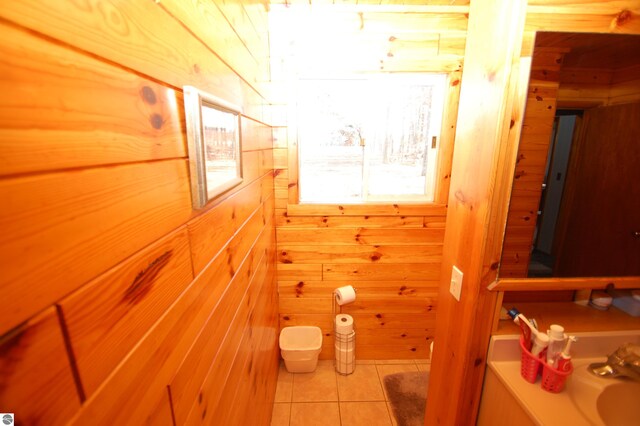 bathroom with tile patterned floors, a wealth of natural light, and wood walls