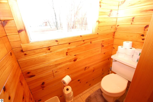 bathroom with tile patterned flooring, toilet, and wooden walls