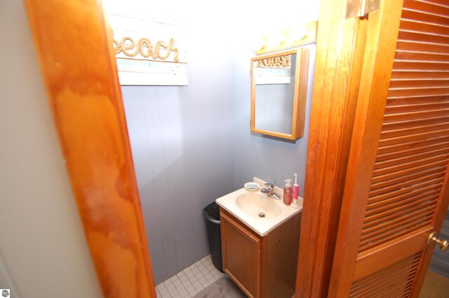 bathroom featuring tile patterned flooring, vanity, and wood walls