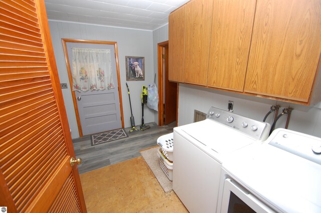 clothes washing area with cabinets, light hardwood / wood-style floors, and washer and clothes dryer