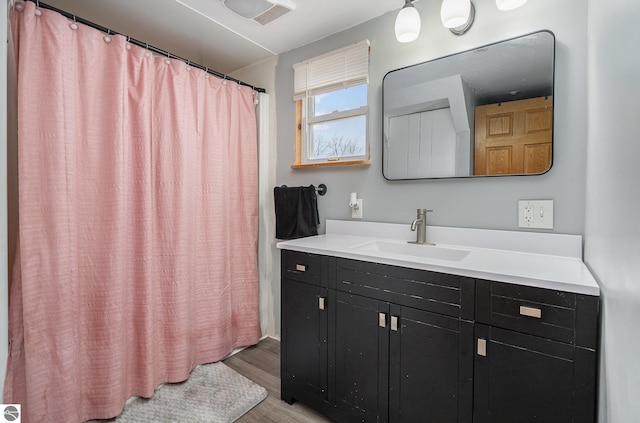 bathroom with hardwood / wood-style floors, vanity, and walk in shower