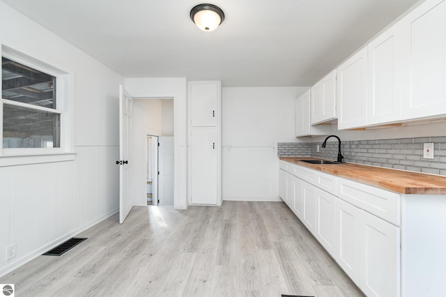 726 Pennsylvania Ave, Alma, MI 48801 - kitchen featuring backsplash, light hardwood / wood-style floors, sink, butcher block countertops, and white cabinetry