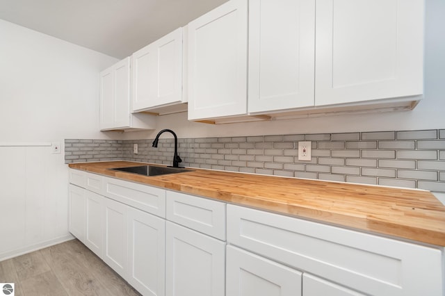 726 Pennsylvania Ave, Alma, MI 48801 - kitchen with light hardwood / wood-style flooring, white cabinetry, sink, and wooden counters