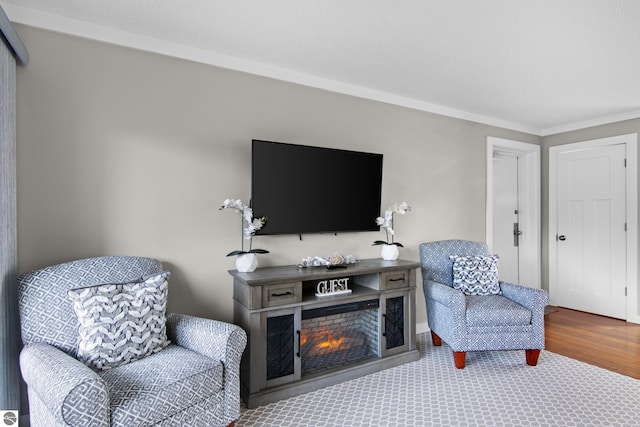 sitting room with wood-type flooring and ornamental molding