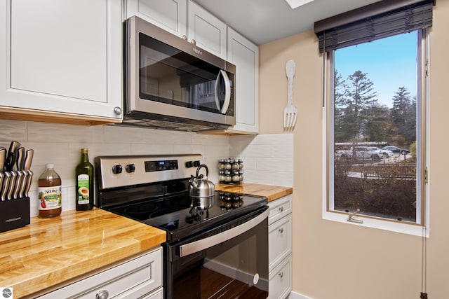 kitchen with white cabinetry, tasteful backsplash, butcher block countertops, appliances with stainless steel finishes, and hardwood / wood-style flooring