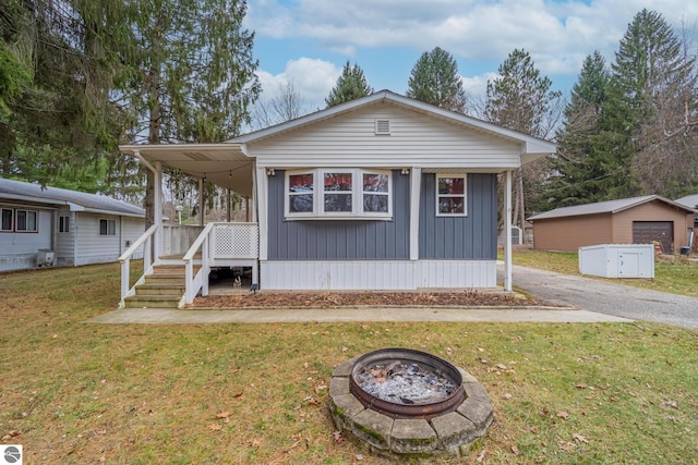 view of front of property with a front yard, an outbuilding, and a fire pit